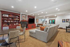 Living area with a glass covered fireplace, stairs, light colored carpet, recessed lighting, and built in features