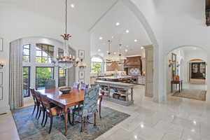 Dining space with arched walkways, a chandelier, a towering ceiling, and recessed lighting