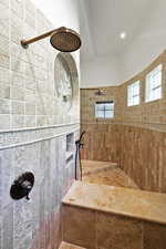 Bathroom with a tile shower, recessed lighting, and tile walls