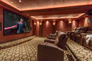 Cinema with ornamental molding, a tray ceiling, recessed lighting, and light carpet