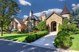 View of front of house featuring stone siding, a front lawn, a high end roof, and a chimney
