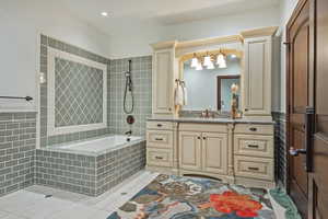 Full bath with vanity, tiled shower / bath, light tile patterned floors, wainscoting, and tile walls