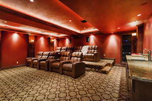 Carpeted home theater featuring ornamental molding, a raised ceiling, and recessed lighting