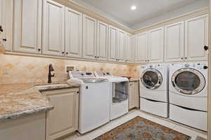 Laundry room with washer and dryer, cabinet space, light tile patterned floors, and recessed lighting