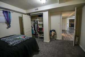 Bedroom with a textured ceiling, dark colored carpet, a closet, and a fireplace