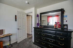 Bedroom featuring dark carpet and a textured ceiling