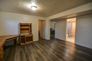 Unfurnished room with a textured ceiling and dark wood-type flooring