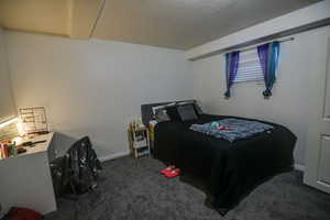 Bedroom with dark carpet and a textured ceiling