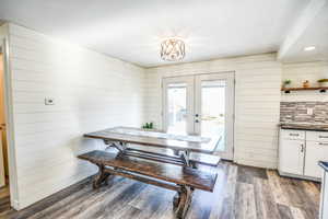 Dining space featuring french doors, dark wood finished floors, and wooden walls