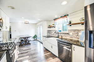 Kitchen with open shelves, white cabinets, stainless steel appliances, french doors, and dark stone counters