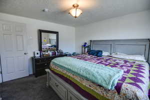 Bedroom with dark carpet and a textured ceiling