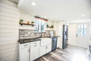 Kitchen featuring open shelves, white cabinets, dark stone counters, appliances with stainless steel finishes, and dark wood-style floors