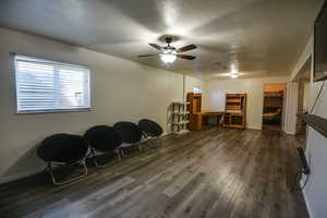 Sitting room with dark wood-style floors, a textured ceiling, and a ceiling fan