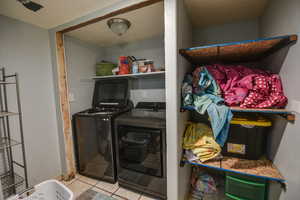 Laundry room featuring light tile patterned floors and washing machine and dryer