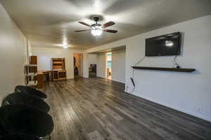 Living room with dark wood-style floors and a ceiling fan