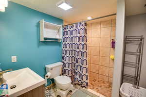 Bathroom featuring a tile shower, vanity, a towel warming rack, tile patterned flooring, and a textured ceiling