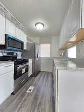 Kitchen with stainless steel range with gas cooktop, white cabinets, and backsplash