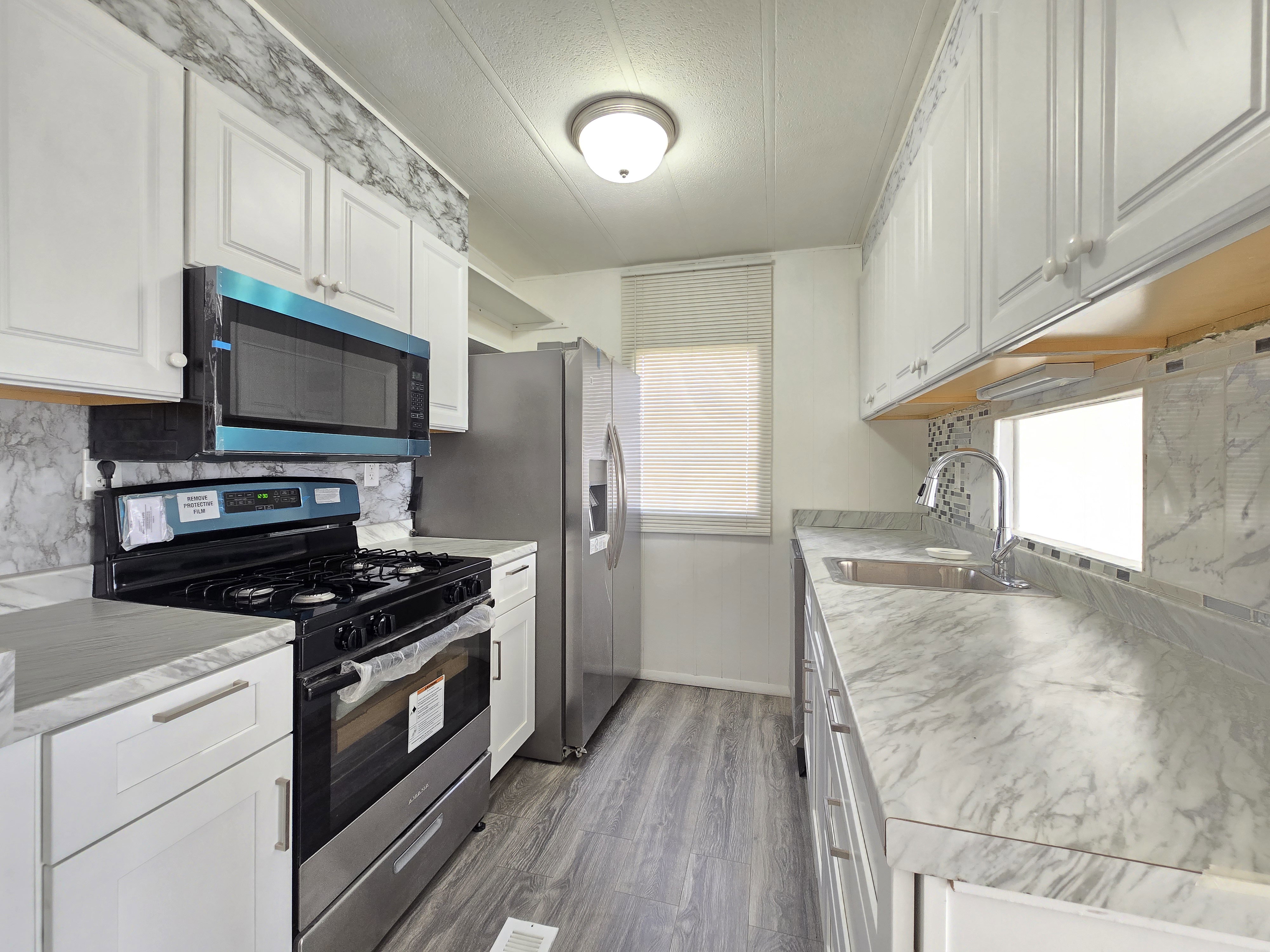 Kitchen featuring stainless steel gas stove, light countertops, and white cabinets