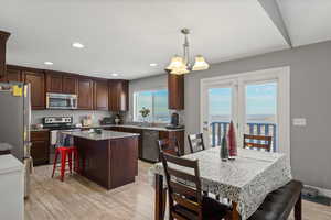 Kitchen with appliances with stainless steel finishes, pendant lighting, a kitchen island, light wood-type flooring, and recessed lighting