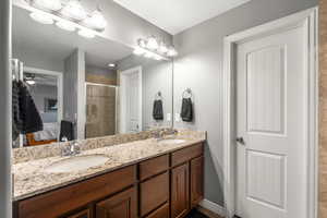 Full bathroom featuring connected bathroom, double vanity, a stall shower, and ceiling fan