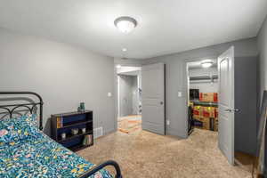 Bedroom featuring light carpet and a walk in closet