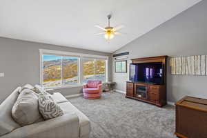 Carpeted living room featuring vaulted ceiling and a ceiling fan