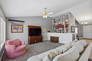 Living room with vaulted ceiling, a chandelier, carpet floors, and a ceiling fan