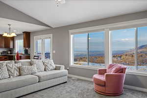 Living area with vaulted ceiling, a chandelier, carpet flooring, and a mountain view