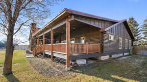View of side of property with board and batten siding, log siding, a chimney, and a porch