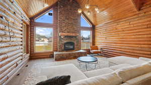 Living area with high vaulted ceiling, an outdoor stone fireplace, wood ceiling, log walls, and healthy amount of natural light