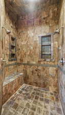 Ensuite Primary Bathroom featuring a tile shower and stone tile flooring