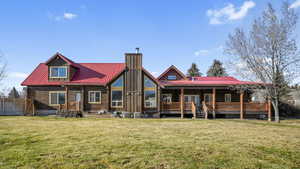 Back of property featuring a metal roof, a porch, a lawn, and a chimney