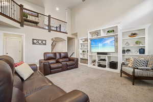 Carpeted living area featuring a high ceiling, built in shelves, and arched walkways