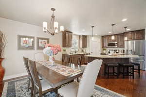 Dining room with dark wood-type flooring, a chandelier, and recessed lighting