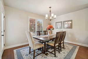 Dining area featuring a chandelier and dark wood-type flooring