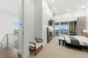 Bedroom featuring access to exterior, a tiled fireplace, recessed lighting, and light carpet