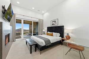 Bedroom with carpet, access to outside, a lit fireplace, and recessed lighting
