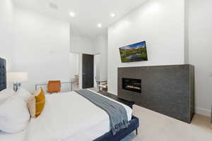 Bedroom with a glass covered fireplace, carpet floors, a towering ceiling, and recessed lighting