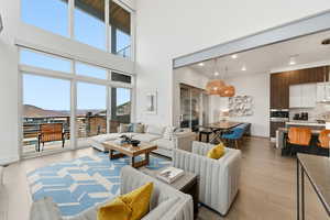 Living area with light wood-style floors, a mountain view, a towering ceiling, and recessed lighting