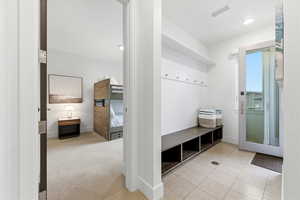 Mudroom with light carpet and light tile patterned floors