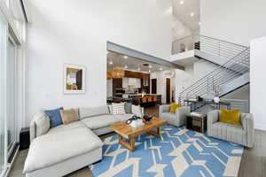 Living area with a high ceiling, wood finished floors, recessed lighting, and stairs