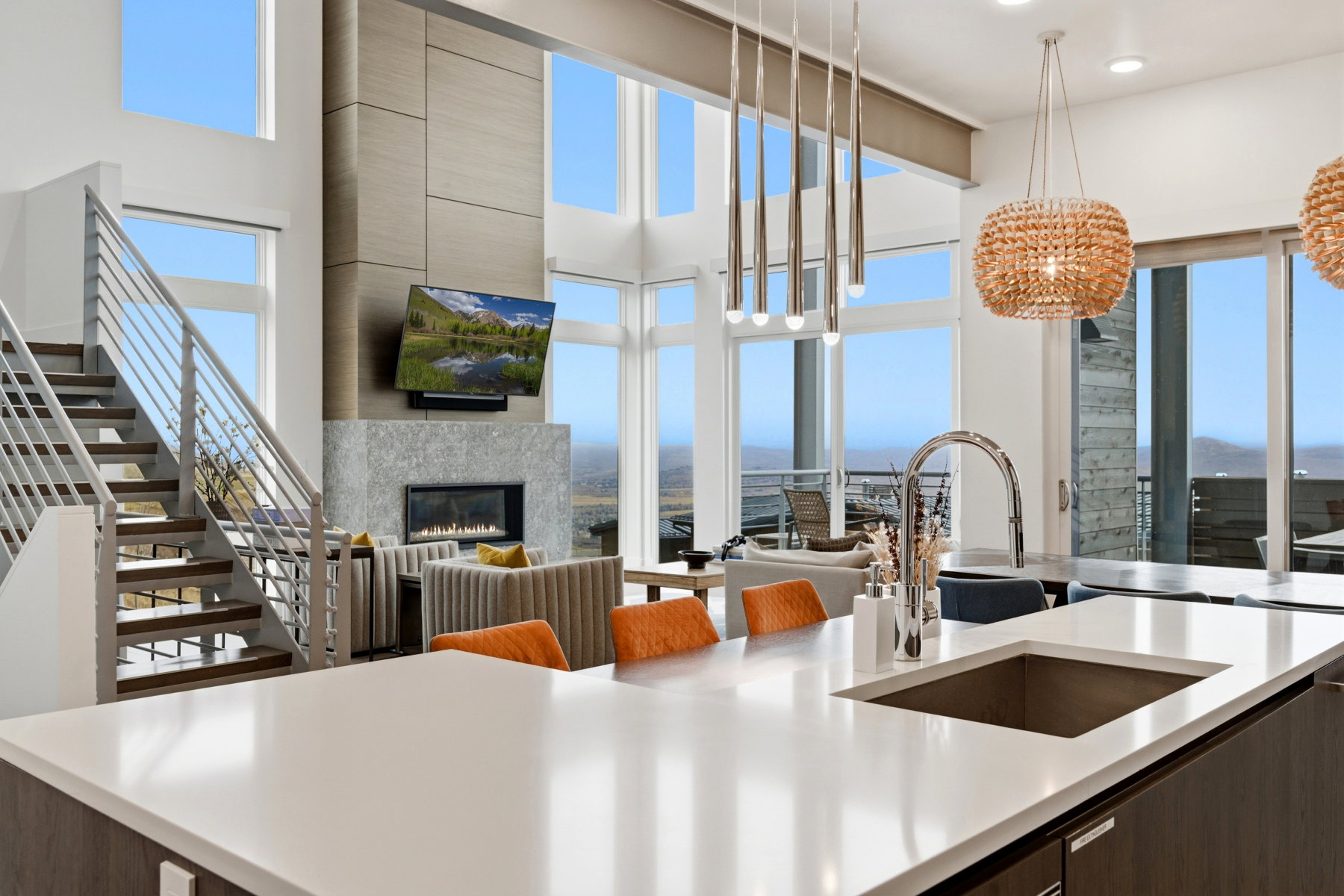 Kitchen featuring modern cabinets, dark brown cabinetry, a glass covered fireplace, decorative light fixtures, and a towering ceiling