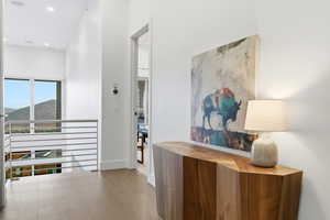 Hallway featuring light wood finished floors, recessed lighting, and an upstairs landing