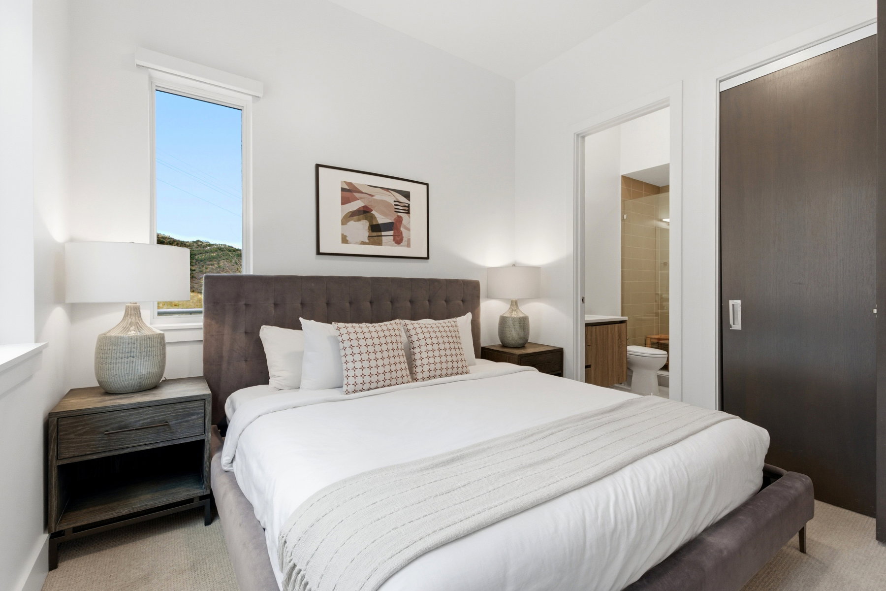 Bedroom with light colored carpet and connected bathroom