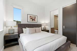 Bedroom with light colored carpet and connected bathroom