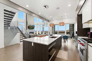 Kitchen featuring modern cabinets, dark brown cabinetry, designer stove, pendant lighting, and built in microwave