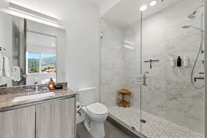 Full bath featuring a marble finish shower, vanity, and recessed lighting