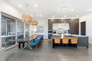 Kitchen with modern cabinets, dark brown cabinets, hanging light fixtures, a large island, and recessed lighting