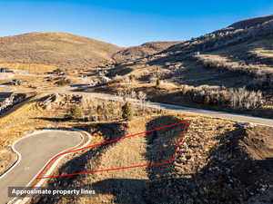 Aerial view of property and surrounding area featuring a mountainous background and property parcel outlined