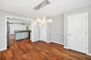 Unfurnished dining area featuring dark wood-style flooring and ceiling fan